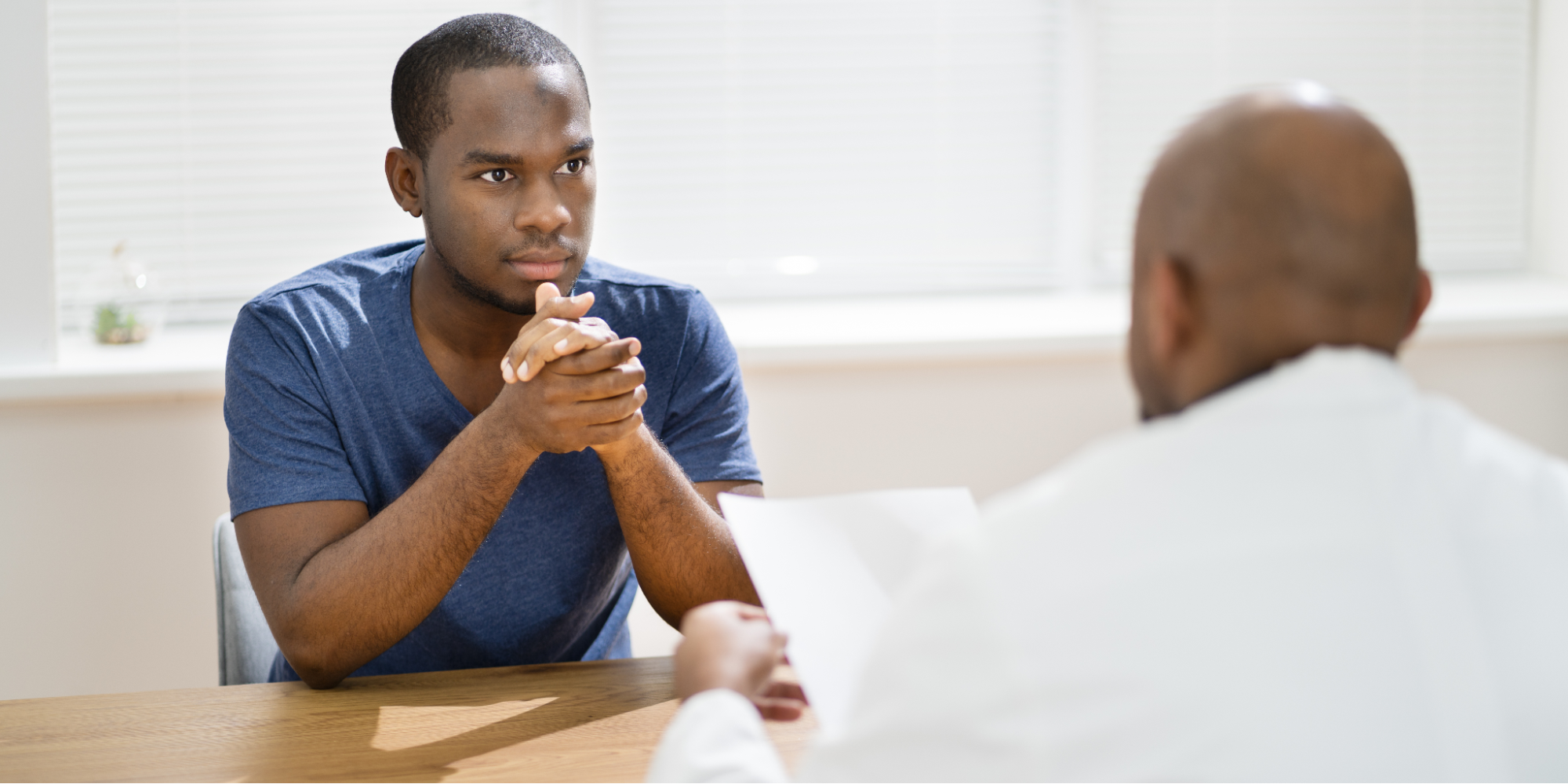 A Black man reviewing medical documents about GFR score and kidney health function with a Black male physician.