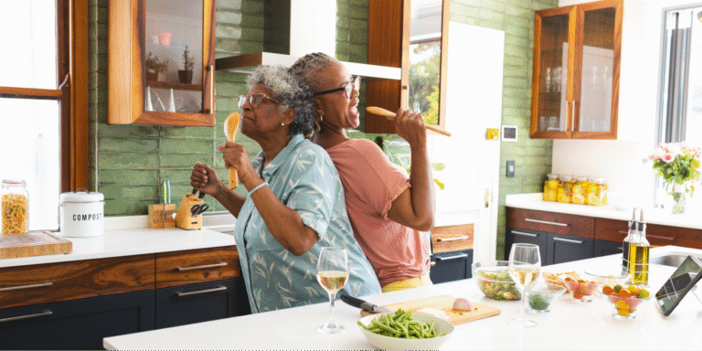 Two Black women enjoying time together in the kitchen while cooking heart-healthy Southern recipes that lower cholesterol.