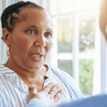 An older Black woman describing physical symptoms of heart failure to a caregiver.