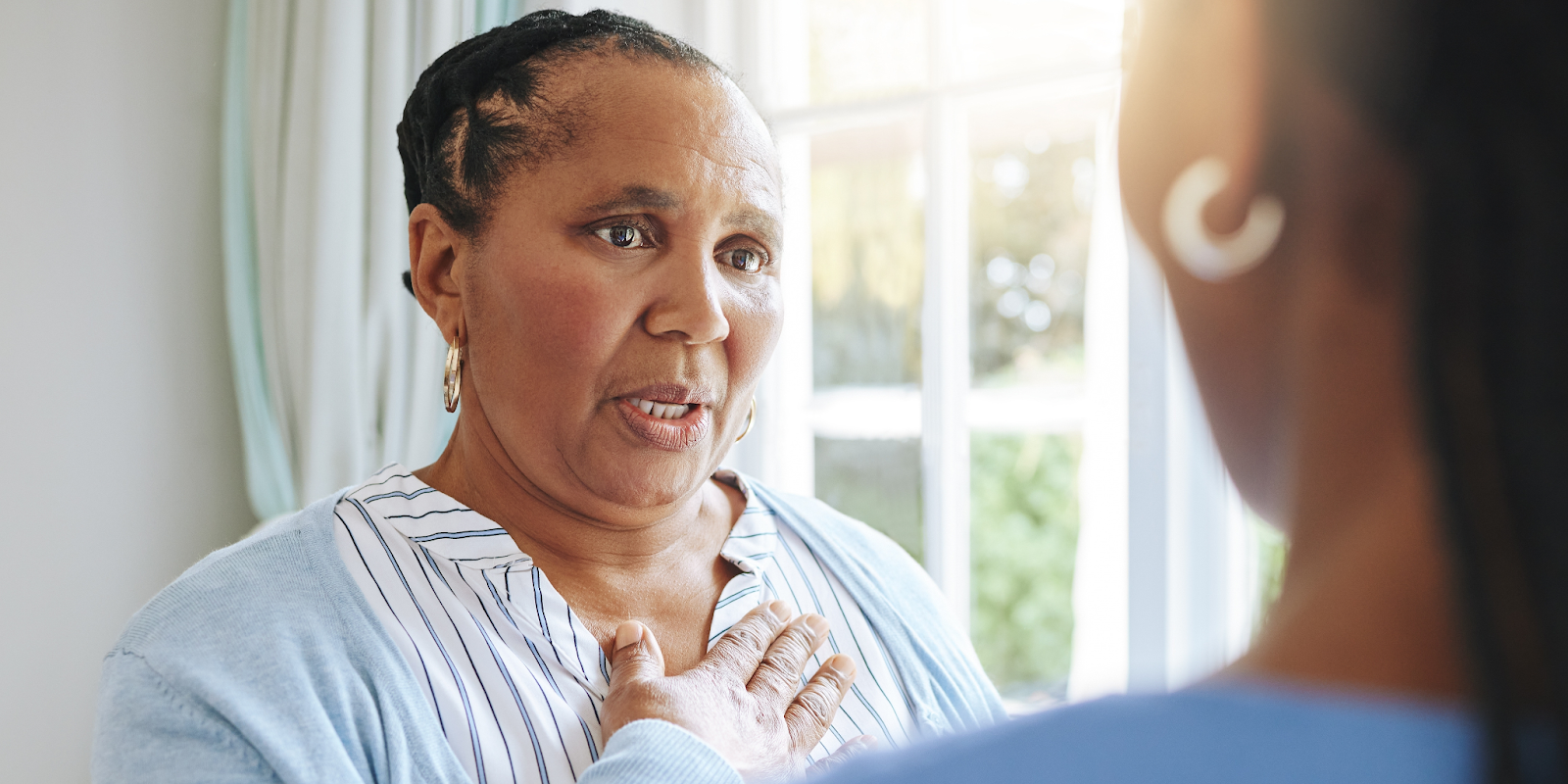 An older Black woman describing physical symptoms of heart failure to a caregiver.