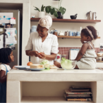 A Black mother with breast cancer preparing a chemo friendly meal with her two young daughters in their home kitchen.