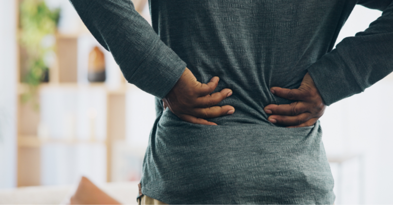 A close-up image of a person clutching their lower back, an early warning sign of where lung cancer spreads in the body.